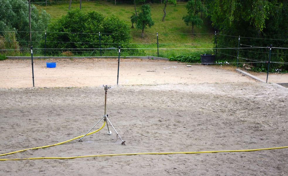 Reitplatz wird mit einem Rasensprenger bewässert