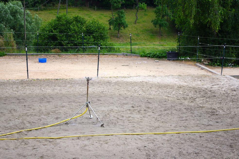 Reitplatz wird mit einem Rasensprenger bewässert