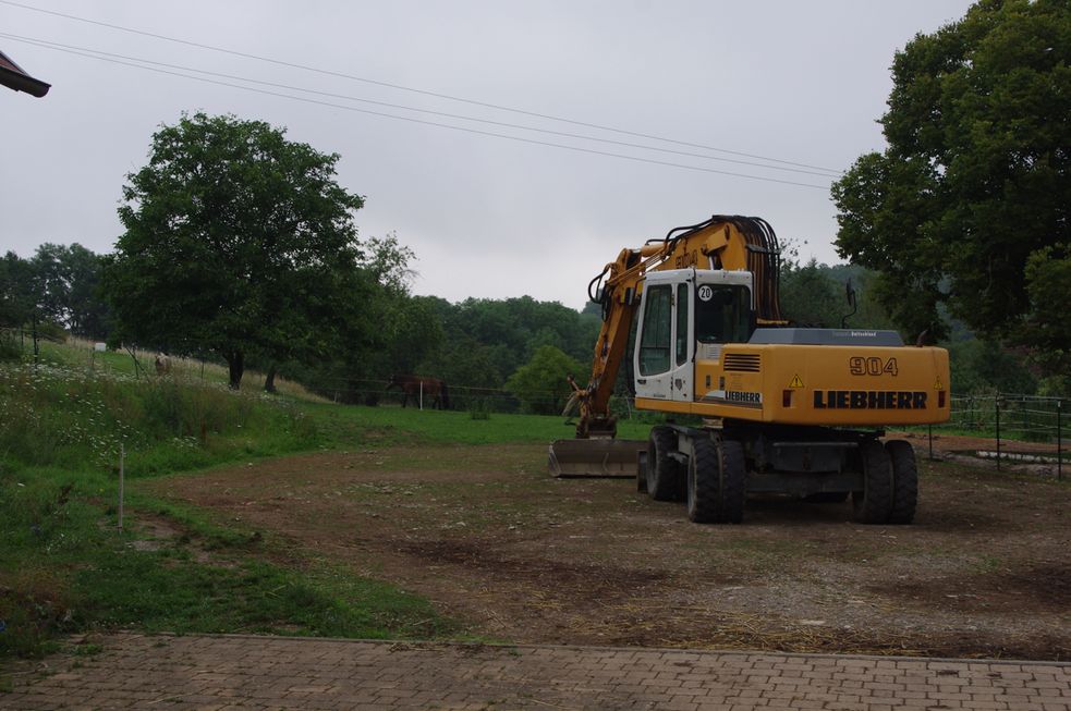 Bagger ebnet den Boden für den Reitplatz